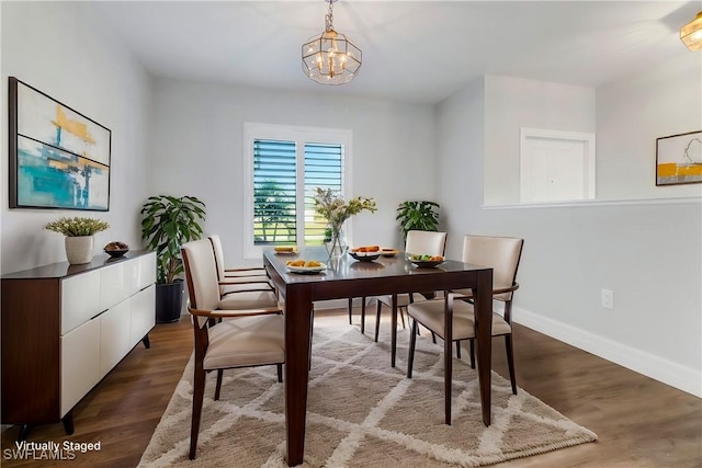 dining area with dark wood-type flooring and a notable chandelier