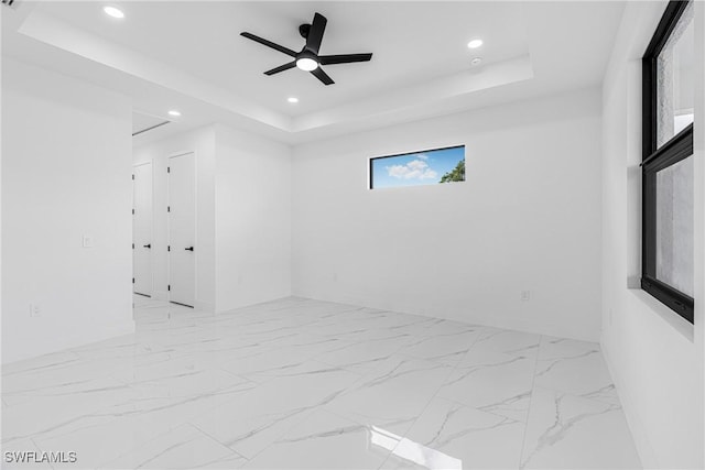 empty room with a tray ceiling and ceiling fan