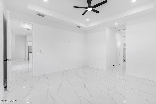 spare room featuring a tray ceiling and ceiling fan