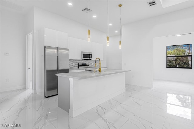 kitchen with pendant lighting, white cabinets, sink, an island with sink, and appliances with stainless steel finishes