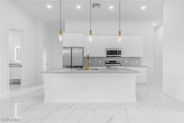 kitchen with a center island with sink, decorative light fixtures, white cabinetry, and appliances with stainless steel finishes