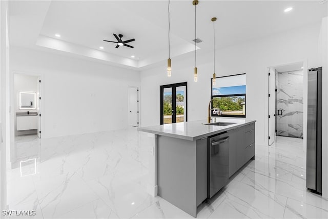 kitchen featuring appliances with stainless steel finishes, a raised ceiling, a kitchen island with sink, and pendant lighting