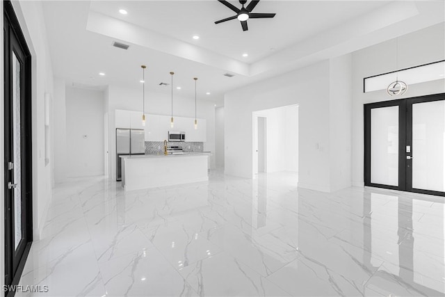 unfurnished living room with french doors, a tray ceiling, and ceiling fan