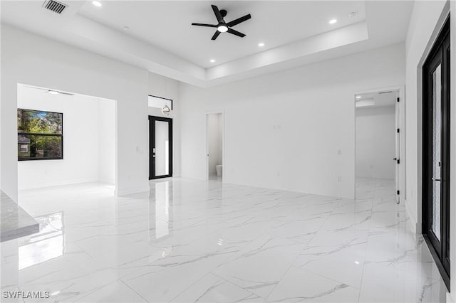 unfurnished room featuring a raised ceiling and ceiling fan