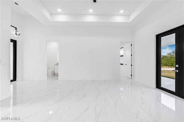 empty room featuring a raised ceiling and a high ceiling