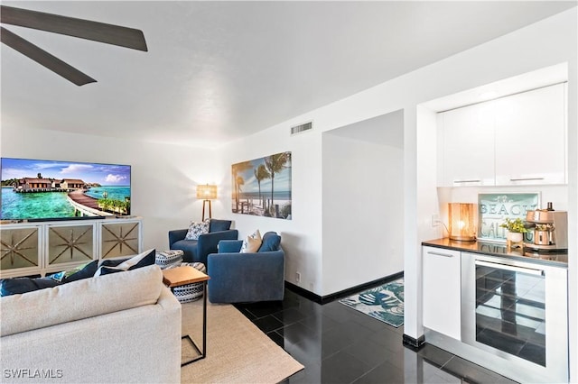 living room with indoor bar, dark tile patterned floors, beverage cooler, and ceiling fan