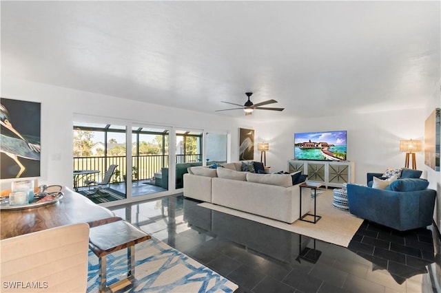 living room with ceiling fan and dark tile patterned floors