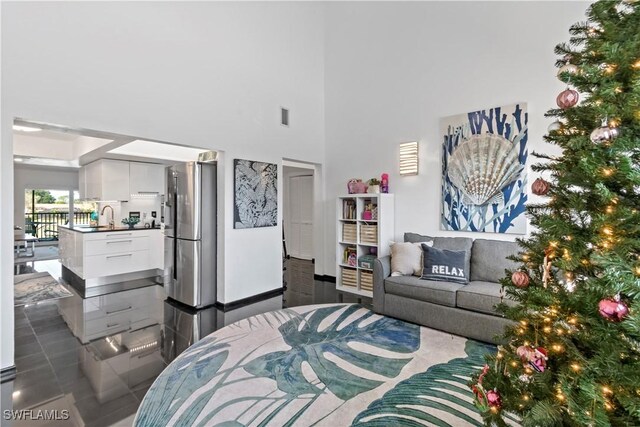 tiled bedroom with a towering ceiling, sink, and stainless steel refrigerator