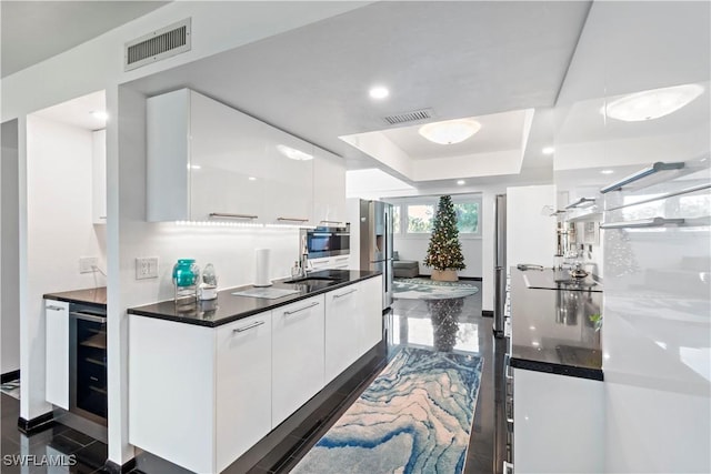 kitchen featuring appliances with stainless steel finishes, sink, white cabinets, and a tray ceiling