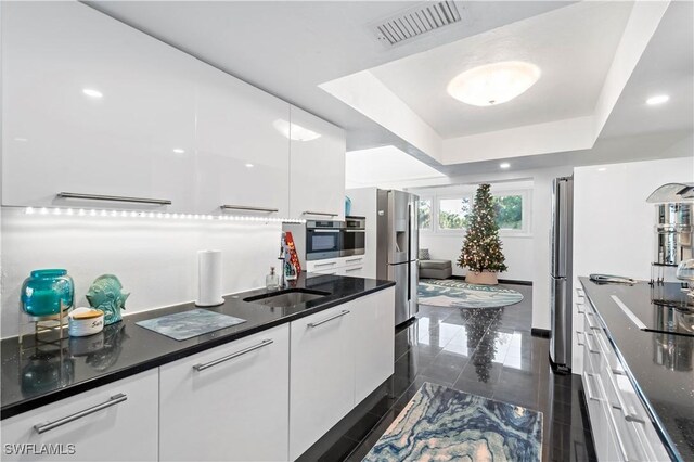 kitchen with white cabinetry, sink, a tray ceiling, and appliances with stainless steel finishes