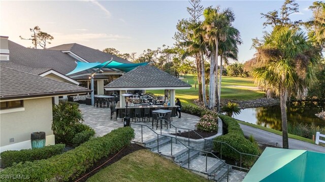 view of community featuring a water view, a gazebo, a yard, exterior bar, and a patio