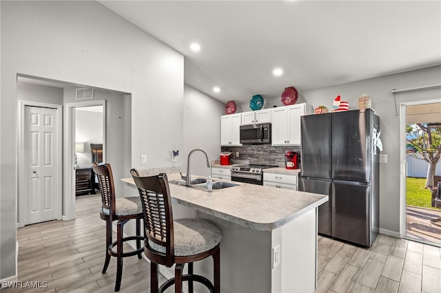 kitchen with sink, a breakfast bar area, stainless steel appliances, white cabinets, and kitchen peninsula