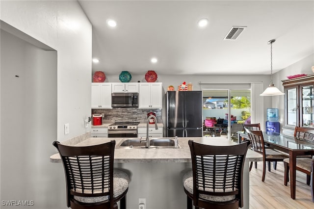 kitchen featuring sink, appliances with stainless steel finishes, white cabinets, pendant lighting, and backsplash