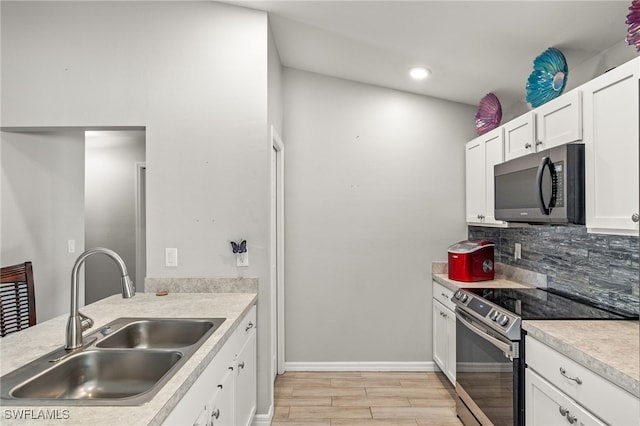 kitchen featuring stainless steel electric stove, sink, decorative backsplash, and white cabinets