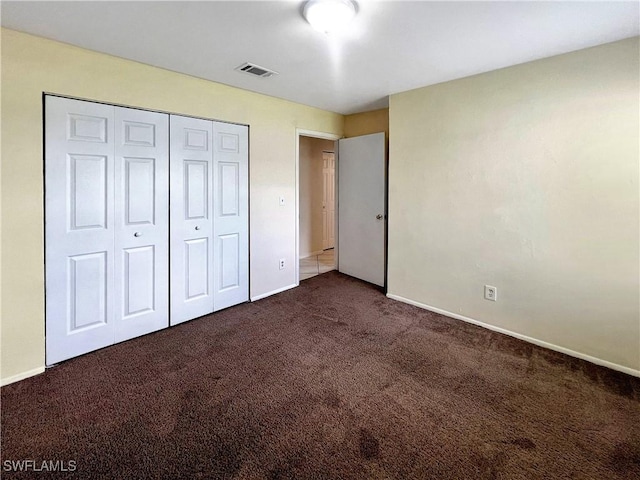 unfurnished bedroom featuring a closet and dark colored carpet