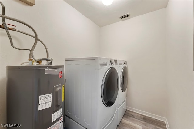 clothes washing area featuring water heater, light hardwood / wood-style flooring, and independent washer and dryer