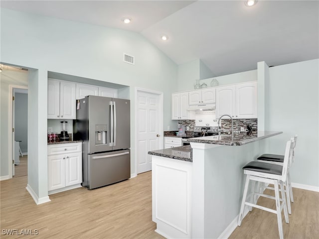 kitchen featuring kitchen peninsula, dark stone counters, stainless steel appliances, light hardwood / wood-style flooring, and white cabinets