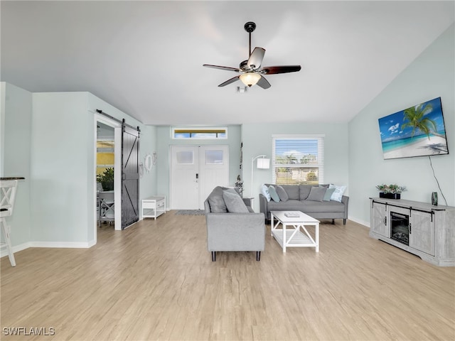 living room featuring a barn door, light hardwood / wood-style flooring, and ceiling fan