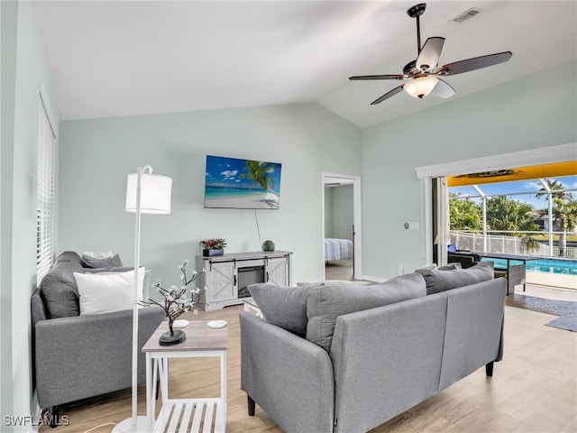 living room featuring ceiling fan, lofted ceiling, and light hardwood / wood-style flooring