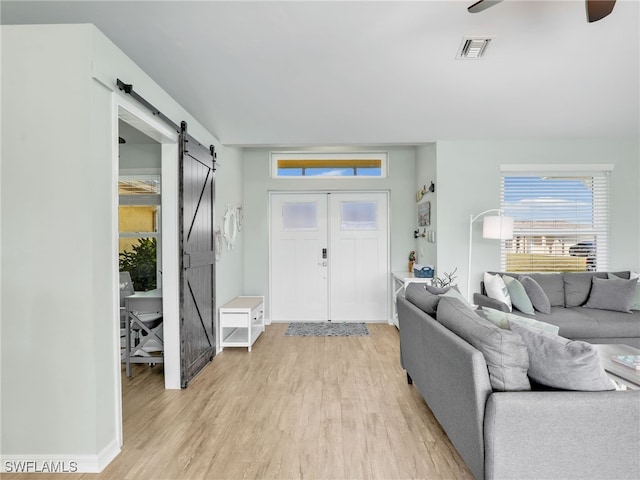 entryway featuring light wood-type flooring, a barn door, and ceiling fan