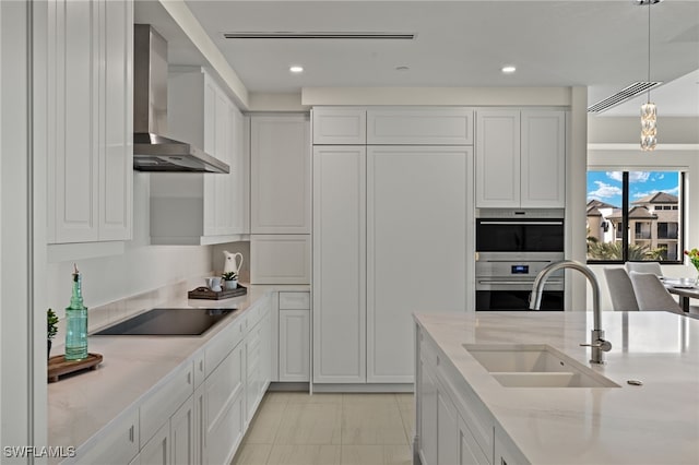 kitchen with white cabinets, hanging light fixtures, wall chimney exhaust hood, and sink