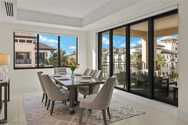 tiled dining space with a tray ceiling