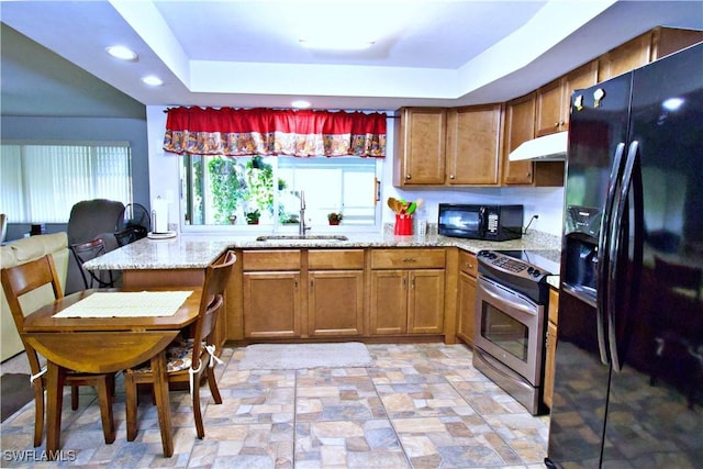 kitchen with kitchen peninsula, sink, light stone countertops, and black appliances