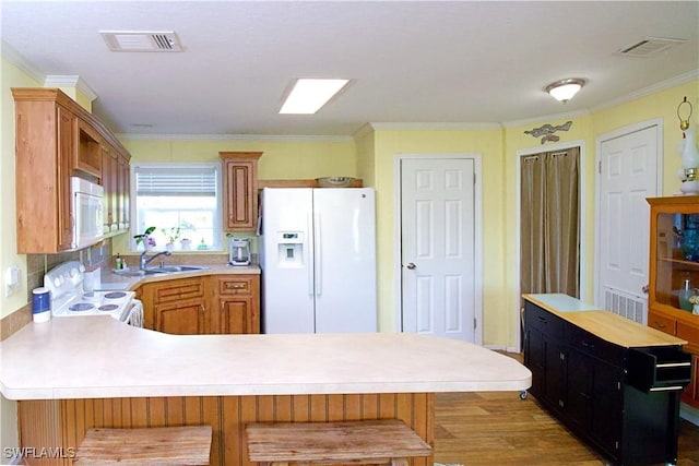 kitchen with sink, a kitchen bar, white appliances, and ornamental molding