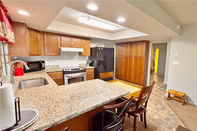 kitchen with black appliances, a raised ceiling, kitchen peninsula, and sink