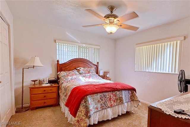 bedroom with ceiling fan, light carpet, and a closet