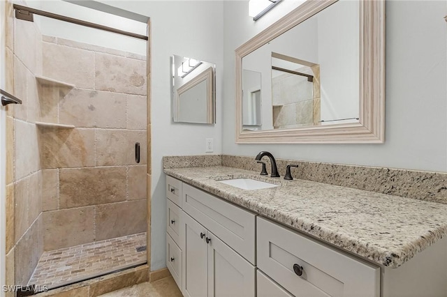 bathroom with a tile shower and vanity