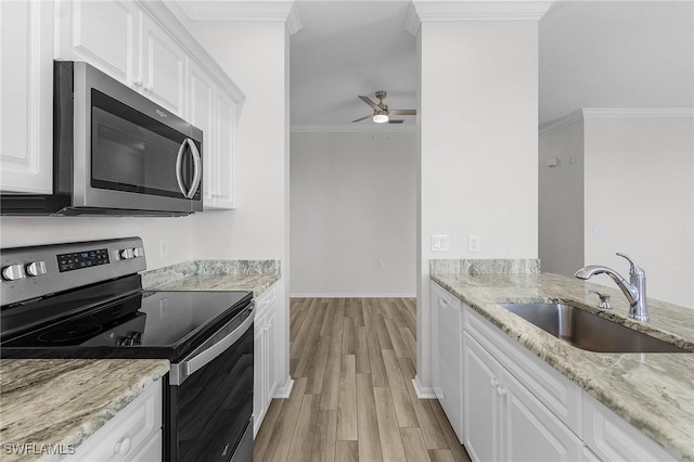 kitchen with light stone countertops, white cabinetry, sink, crown molding, and appliances with stainless steel finishes