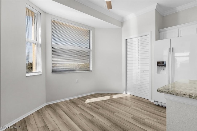 kitchen featuring light wood-type flooring, light stone counters, ornamental molding, white refrigerator with ice dispenser, and white cabinetry