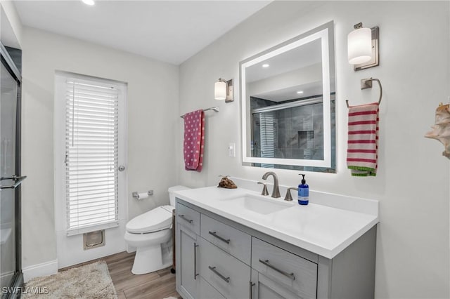 bathroom featuring a healthy amount of sunlight, vanity, wood-type flooring, and toilet