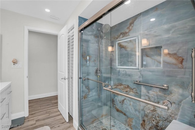 bathroom with wood-type flooring, vanity, and a shower with shower door