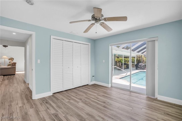 unfurnished bedroom with access to exterior, ceiling fan, a closet, and light wood-type flooring