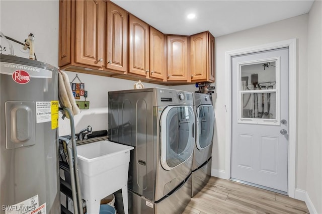 clothes washing area with sink, cabinets, washing machine and dryer, electric water heater, and light hardwood / wood-style floors