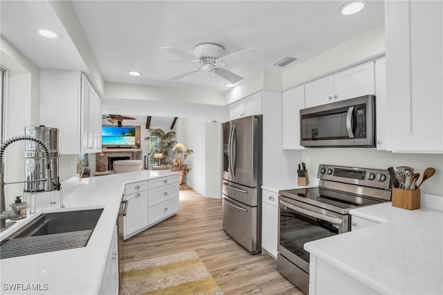 kitchen featuring white cabinetry, sink, stainless steel appliances, and light hardwood / wood-style floors