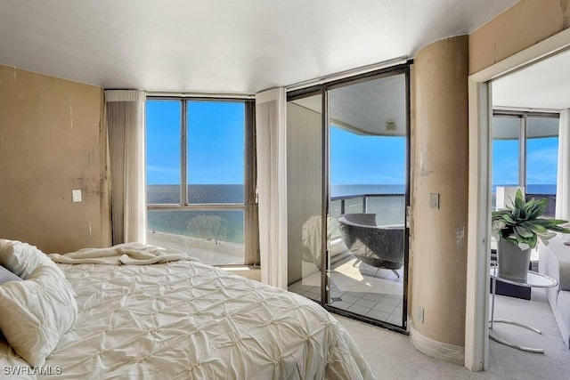 carpeted bedroom with access to outside, multiple windows, and a water view