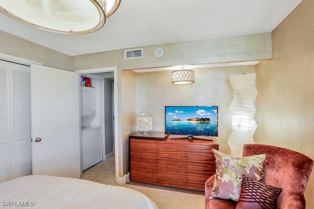 carpeted bedroom with a closet and stacked washer / drying machine