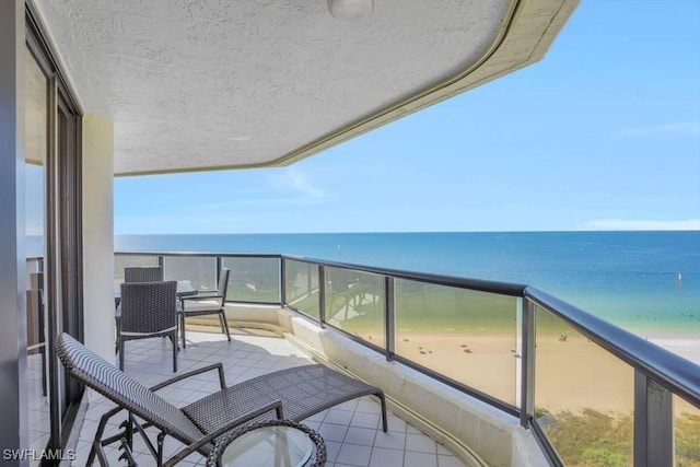 balcony with a water view and a view of the beach