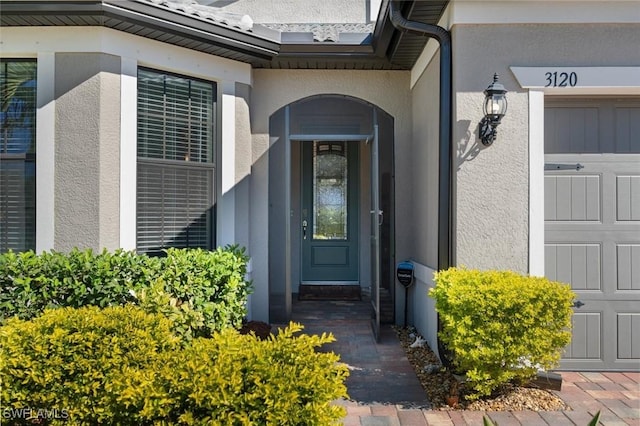 view of exterior entry featuring a garage and stucco siding