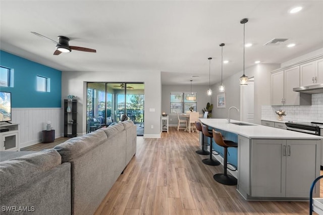 living room with sink, light hardwood / wood-style floors, and ceiling fan