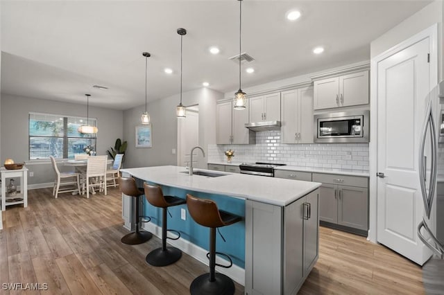 kitchen featuring gray cabinetry, sink, stainless steel appliances, and hanging light fixtures