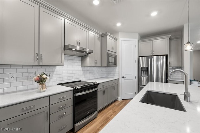 kitchen featuring sink, gray cabinets, pendant lighting, stainless steel appliances, and light stone countertops