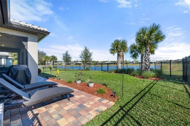 view of yard with a water view, fence, and a patio