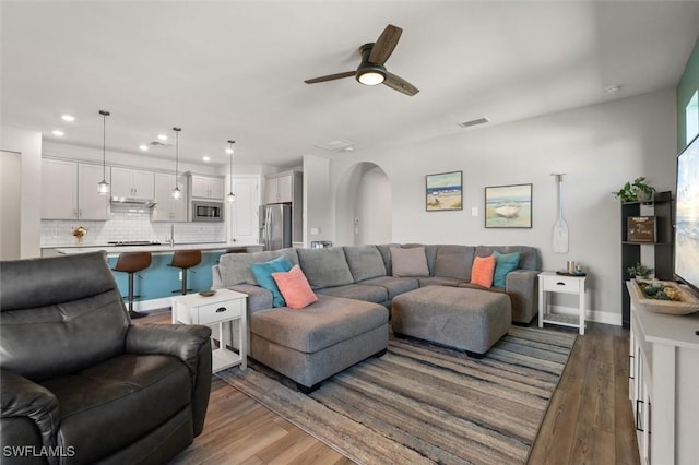 living room featuring ceiling fan and dark hardwood / wood-style flooring