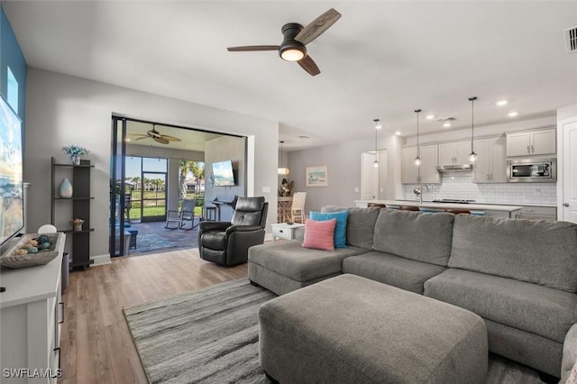 living room with ceiling fan and light hardwood / wood-style floors