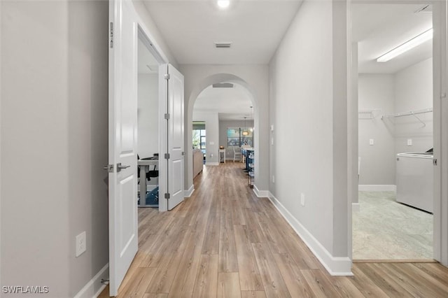 hallway with washer / dryer and light hardwood / wood-style floors