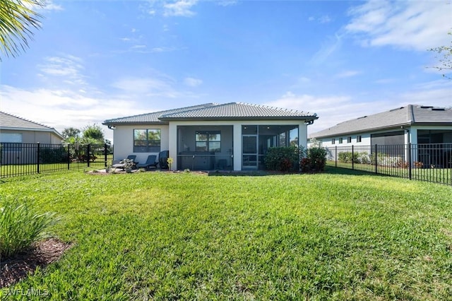 back of house featuring a sunroom, a fenced backyard, a yard, and a tiled roof